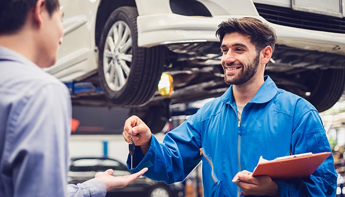 Service technician handing keys back to customer - Finnegan Chevrolet Buick GMC in Rosenberg TX